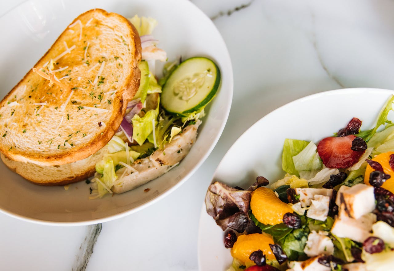Fresh toasted sandwich with lettuce, cucumber, and a vibrant chicken salad on the side.